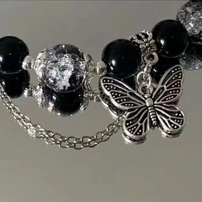 A black beaded bracelet with bohemian style, adorned with silver butterfly pendants and chain details.