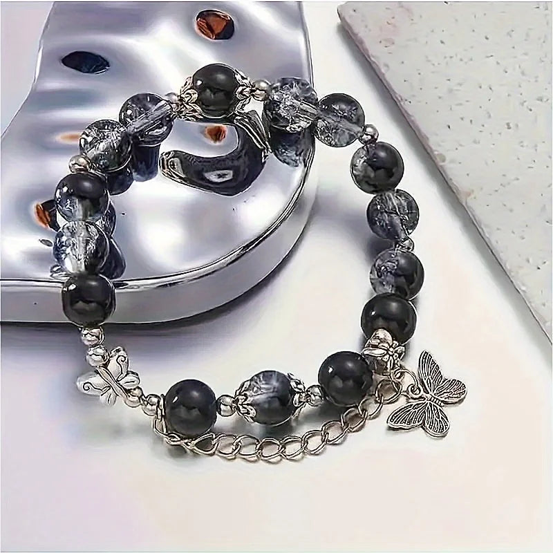 A black beaded bracelet with bohemian style, adorned with silver butterfly pendants and chain details.