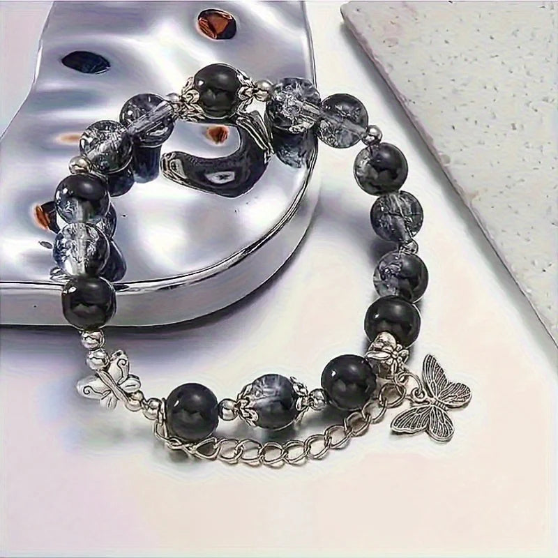 A black beaded bracelet with bohemian style, adorned with silver butterfly pendants and chain details.